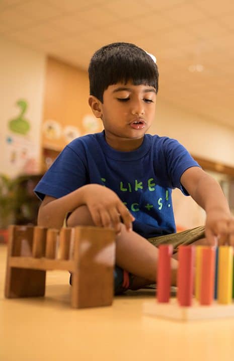 A boy in a blue shirt  of  elementary grade exploring the IB Board activity by arranging the colour bars at his school